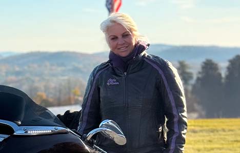 Riding posing with motorcycle in front of flag