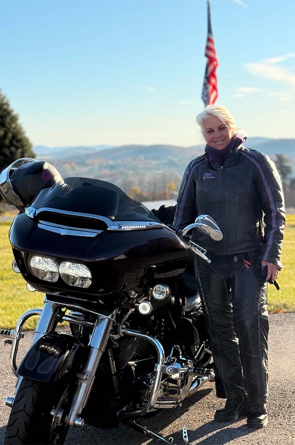 Riding posing with motorcycle in front of flag