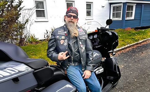 two-tales-thumb Biker leaning on his bike in front of house